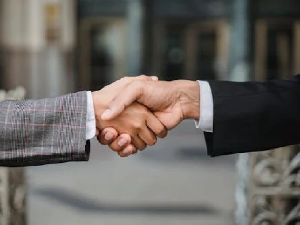 Two people in business suits shake hands.